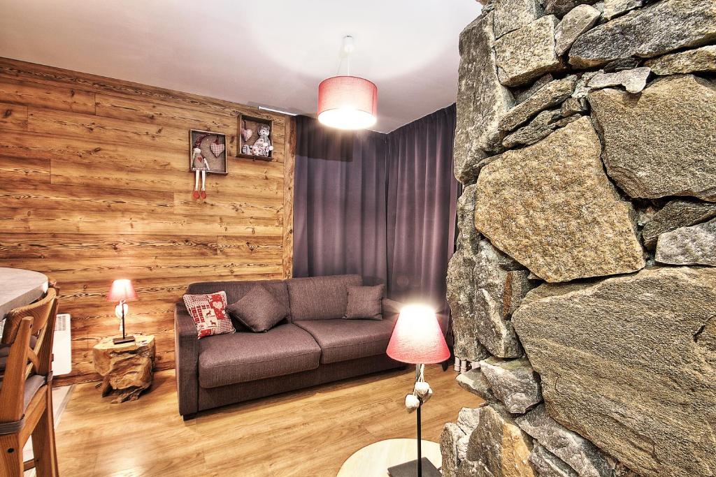 a living room with a couch and a stone wall at Appartements résidence Roches Rouges in Tignes