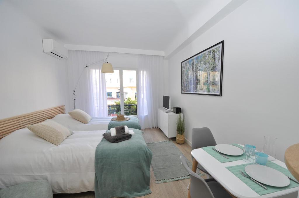 a white bedroom with two beds and a table at 9 Rue Buttura in Cannes