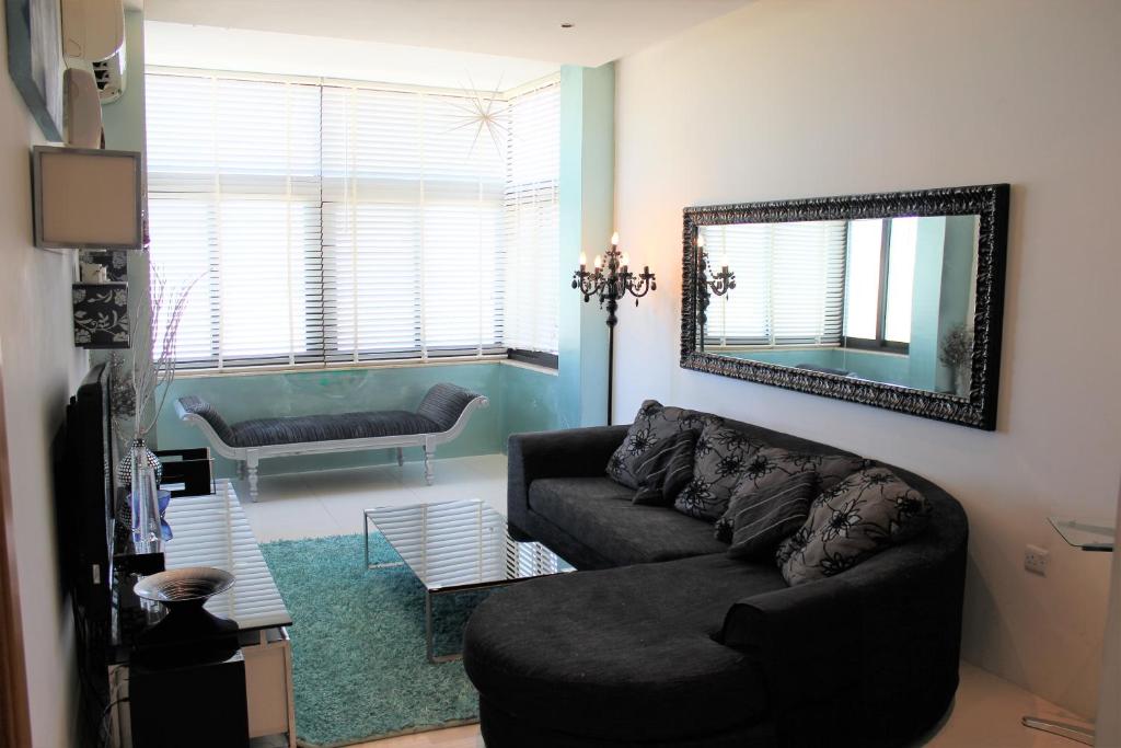 a living room with a couch and a mirror at Sunny Lodge Apartment in St. Paul's Bay
