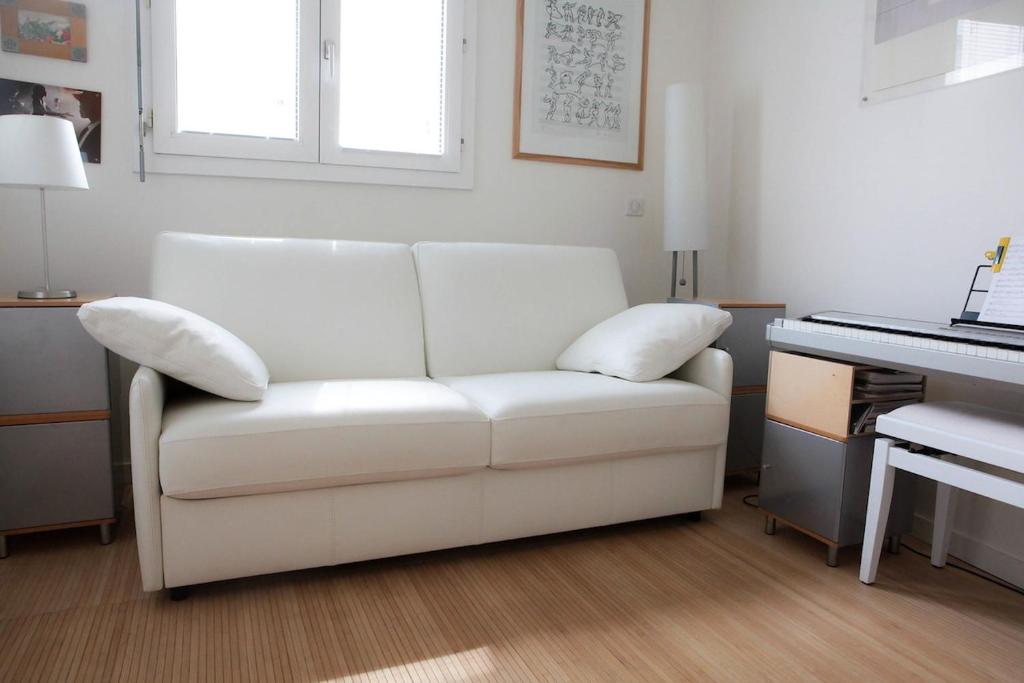 a white couch sitting in a living room next to a piano at Apartment with terrace 5 people Bastille by Weekome in Paris