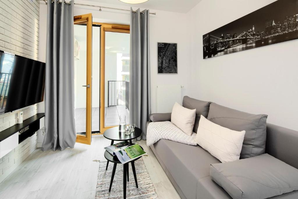 een woonkamer met een bank en een tv bij Native Apartments Lubelska 10 in Krakau