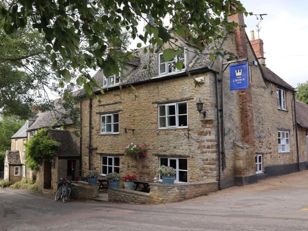 an old brick building with a bike parked in front of it at The Crown Inn, Church Enstone in Chipping Norton