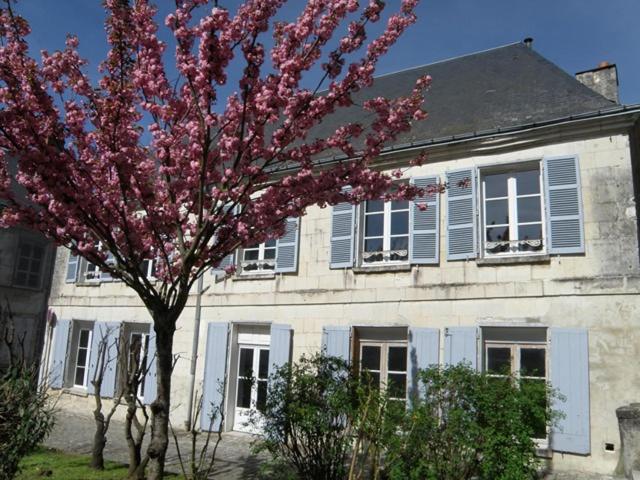 uma árvore com flores cor-de-rosa em frente a um edifício em La Closerie Saint Jacques em Loches