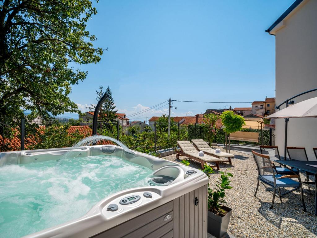 - un bain à remous sur une terrasse avec une table et des chaises dans l'établissement Holiday Home Amberg by Interhome, à Kastav
