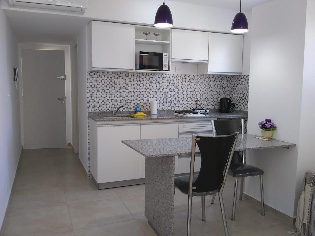 a kitchen with white cabinets and a counter and chairs at Pasco 1847 Apartamento 5B in Rosario