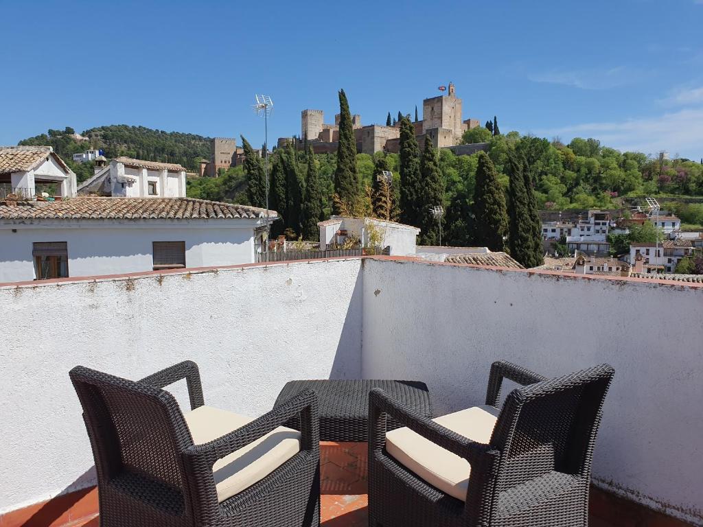 einen Balkon mit 2 Stühlen und einem Tisch an der Wand in der Unterkunft Casa del Aljarife in Granada
