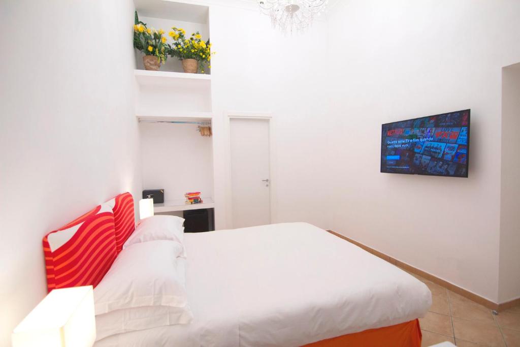 a white bedroom with a bed with red and white pillows at Casa Sorrentina in Sorrento