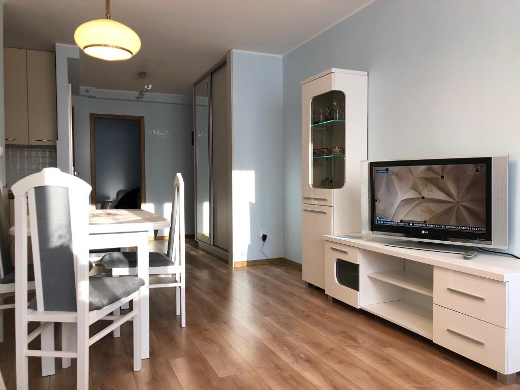 Apartament Sopot Kraszewskiego في سوبوت: غرفة معيشة مع تلفزيون وطاولة مع كراسي