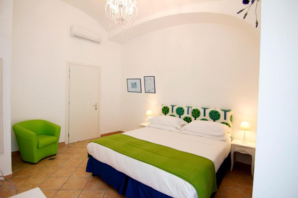 a bedroom with a large bed and a green chair at Casa Sorrentina in Sorrento
