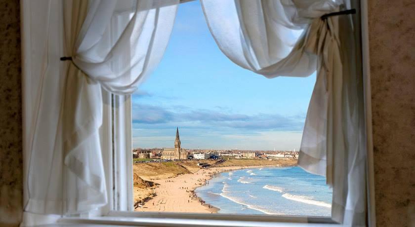 a window with a view of a beach and the ocean at Tynemouth Grand Hotel in Tynemouth