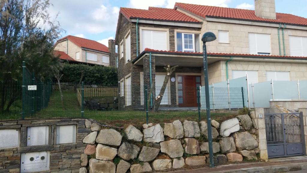 a house with a stone wall and a street light at CHALETS PLAYA GALIZANO in Galizano