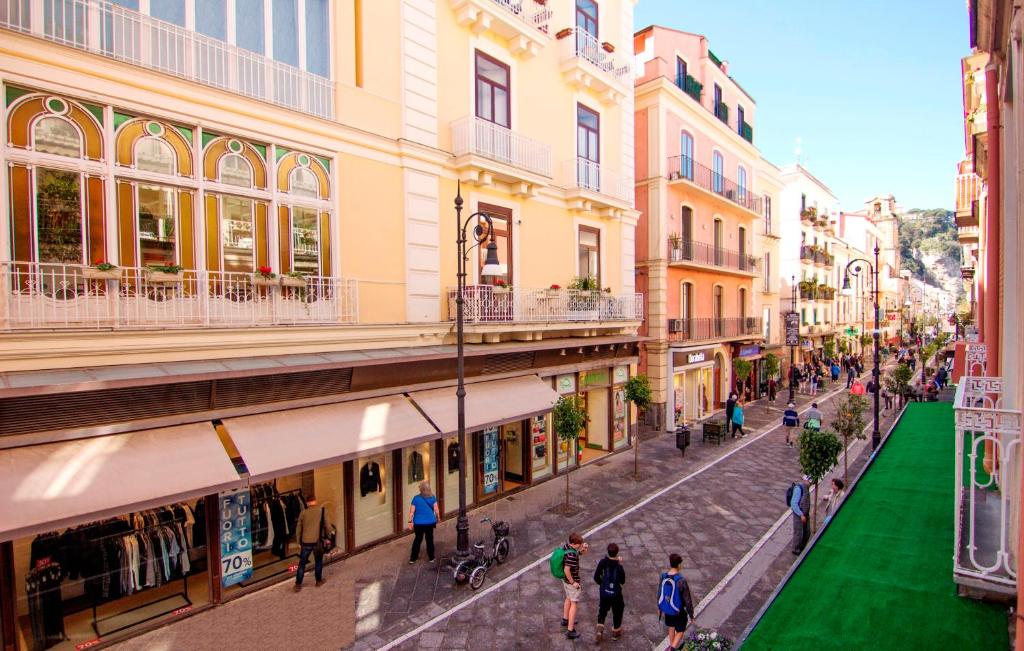 un gruppo di persone che camminano per una strada con edifici di Casa Sorrentina a Sorrento