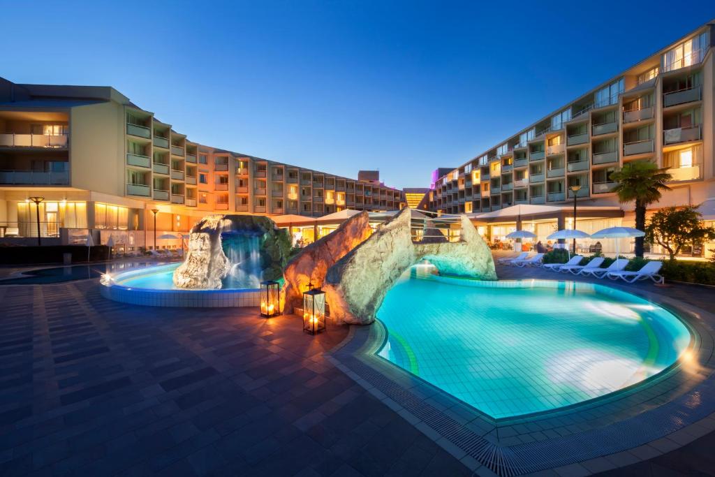 a hotel with a pool in front of a building at Aminess Vival Maestral Hotel in Novigrad Istria