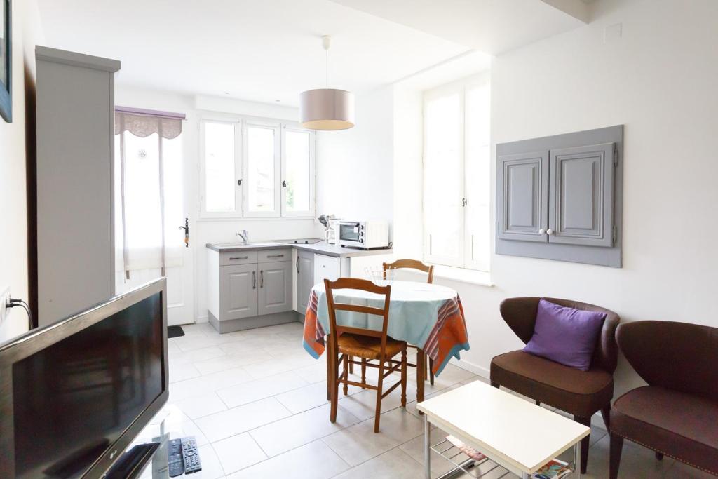 een woonkamer met een tafel en stoelen en een keuken bij Studio Le Nid du Saleys in Salies-de-Béarn