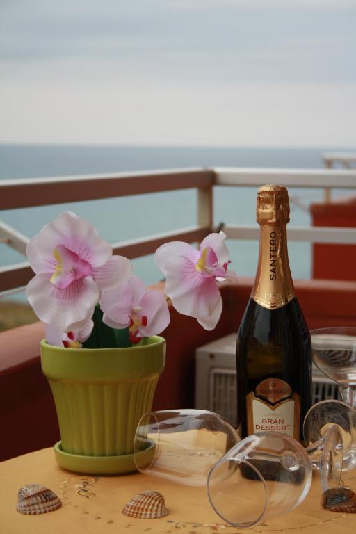 a bottle of wine and a vase with flowers on a table at GB Case Vacanze Sicilia in Balestrate