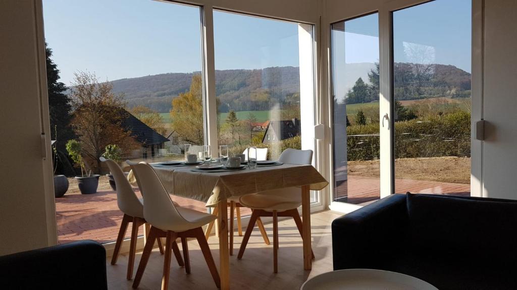 einen Esstisch mit weißen Stühlen und ein großes Fenster in der Unterkunft Ferienwohnung Schreiber in Hessisch Oldendorf