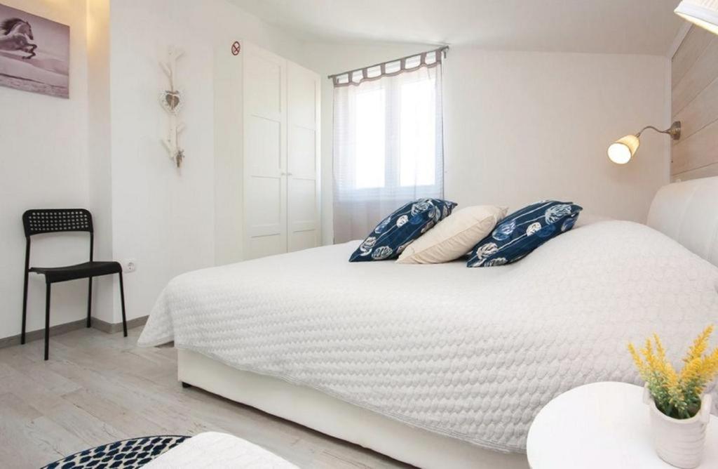 ein weißes Schlafzimmer mit einem großen weißen Bett mit blauen Kissen in der Unterkunft Apartmani Riva in Rogoznica