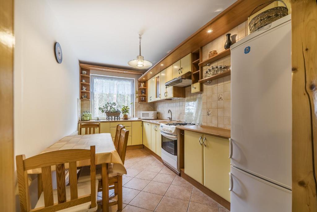 a kitchen with a table and a white refrigerator at Apartament Litoral Jurata in Jurata