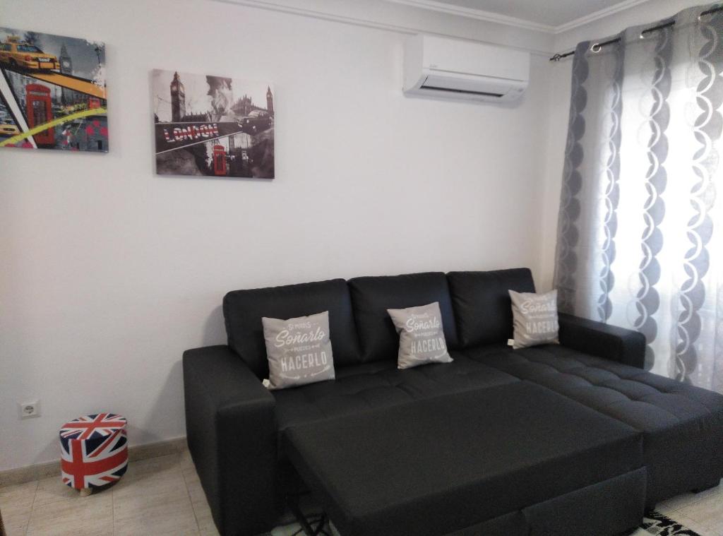 a living room with a black couch in a room at Residencial los olivos in Cala de Finestrat