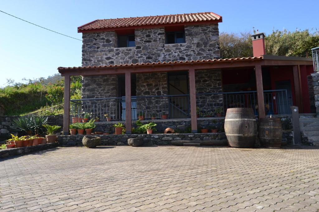 ein Steinhaus mit einer Veranda und einem Fass in der Unterkunft Recantos do Castanheiro in Porto Moniz