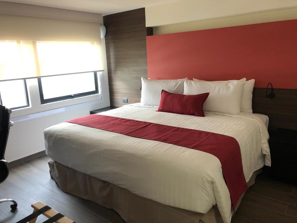 um quarto com uma cama grande e uma parede vermelha em MC Suites Mexico City em Cidade do México