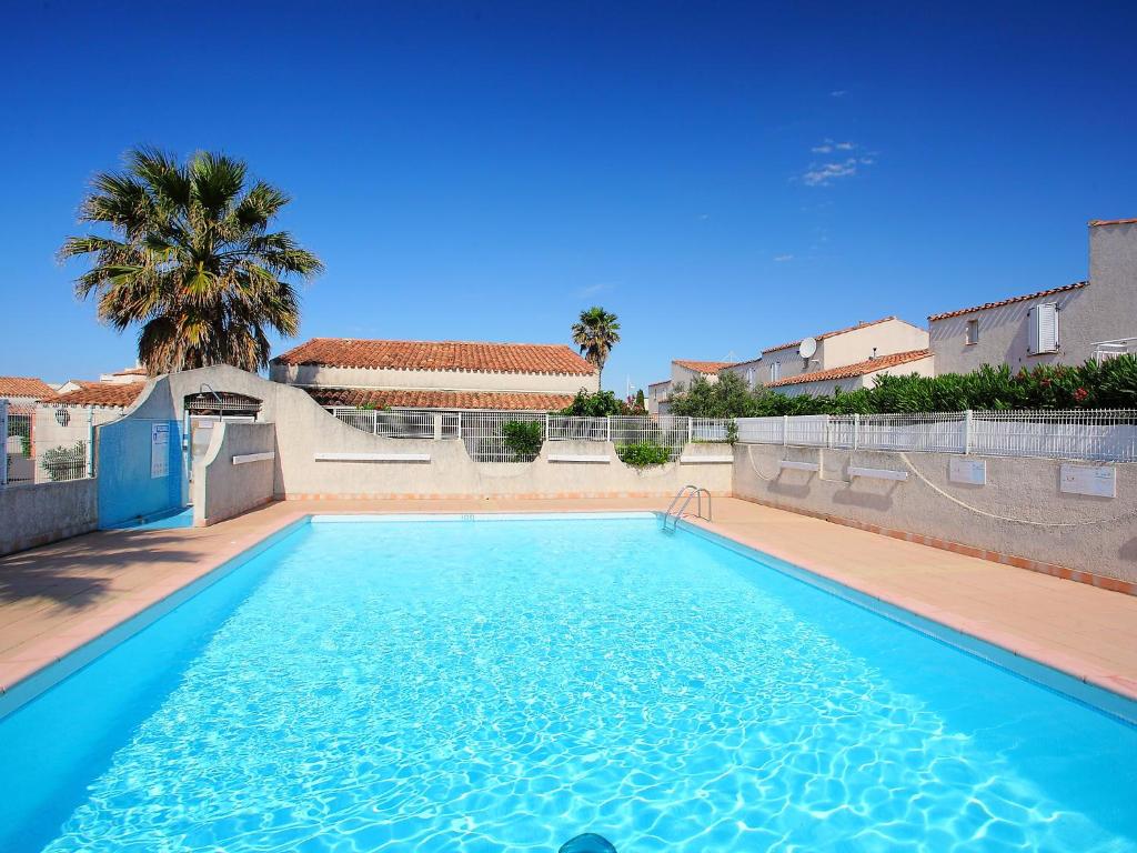 a swimming pool with blue water in a yard at Holiday Home Hacienda Beach II-4 by Interhome in Cap d'Agde