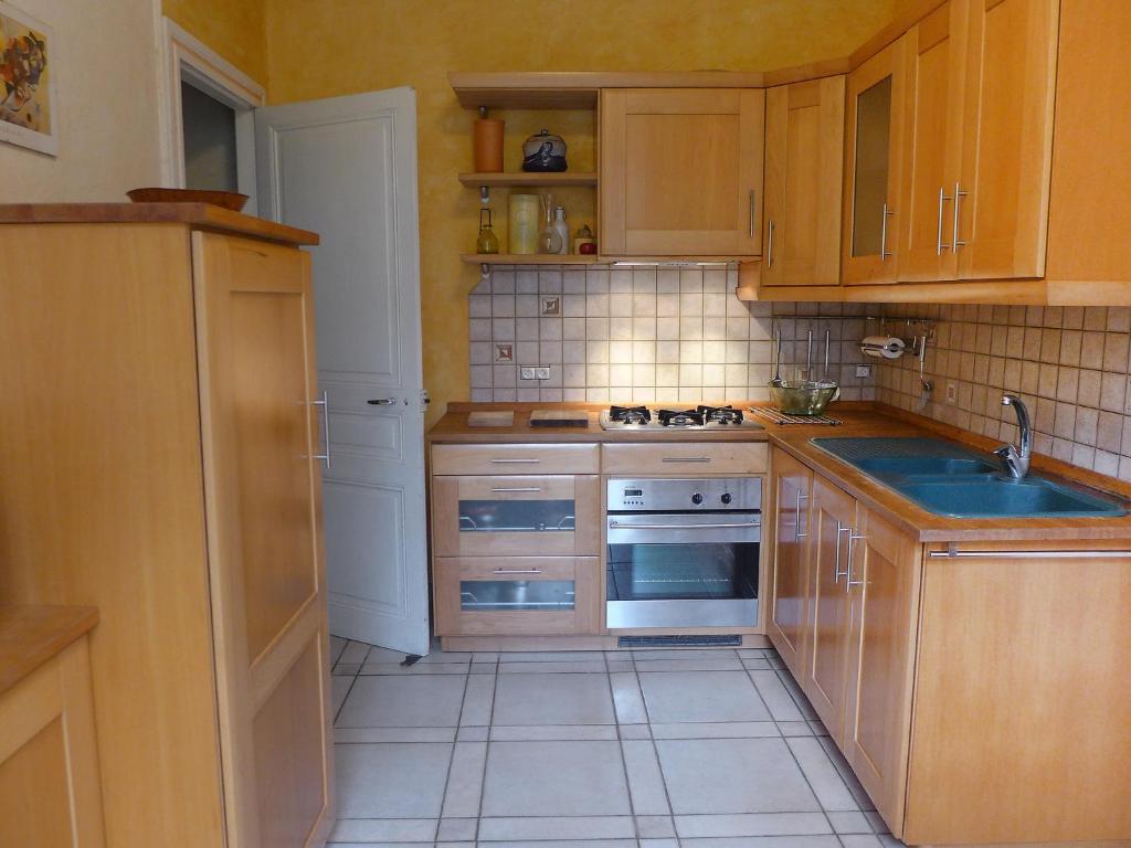 a small kitchen with wooden cabinets and a sink at Holiday Home Le chant des milans by Interhome in Ondres