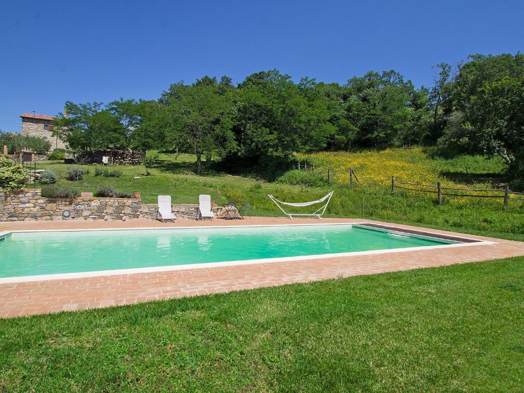 a swimming pool in a yard with two lawn chairs at Holiday Home Casalini by Interhome in Montorgiali