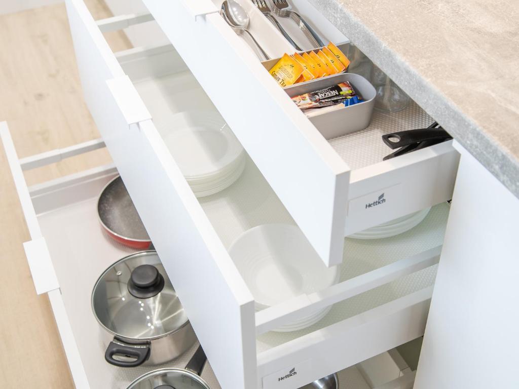 an open kitchen drawer with white shelves at Apartamenty Baltia Kołobrzeg - Bliżej Morza in Kołobrzeg