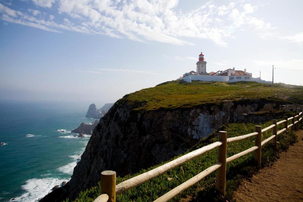 a lighthouse on top of a cliff next to the ocean at Hotel Fortaleza do Guincho Relais & Châteaux in Cascais