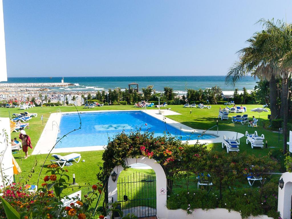 a swimming pool in a park with the ocean in the background at Apartment Cabopino-1 by Interhome in Marbella