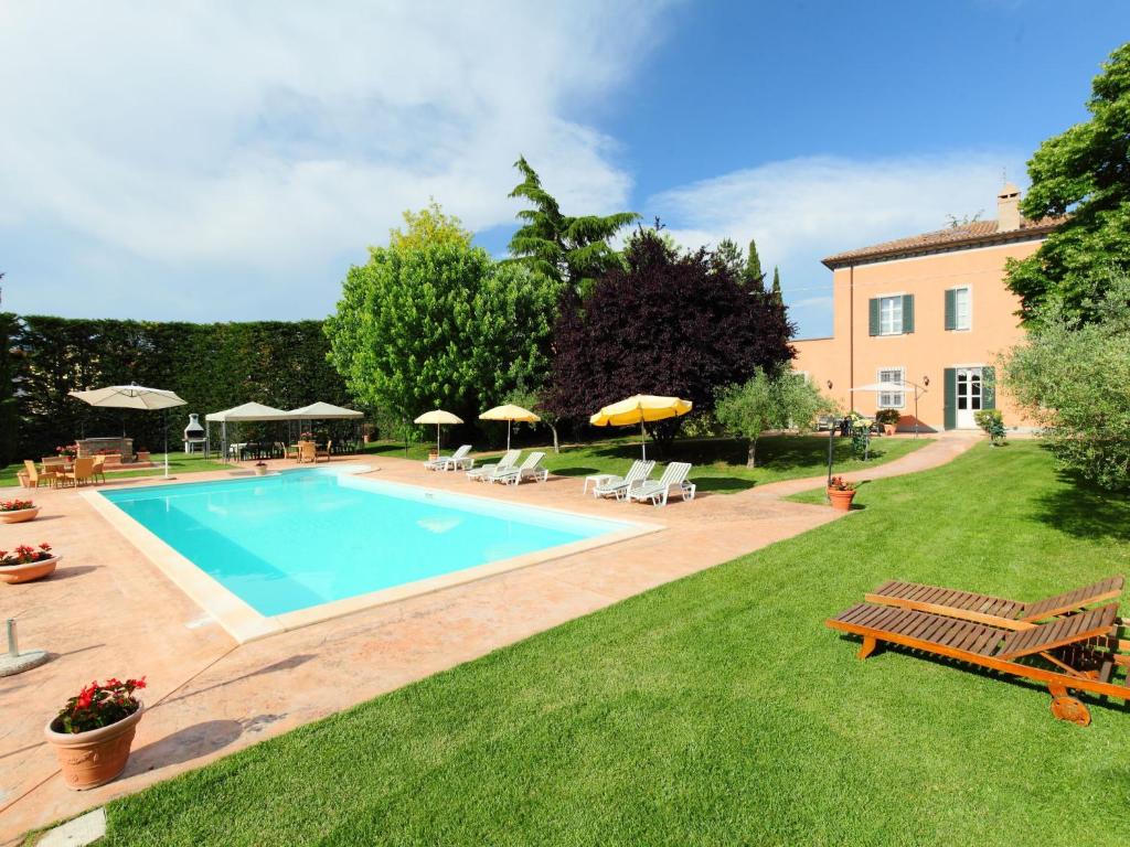 una piscina in un cortile con sedie e ombrelloni di Villa Paolotti by Interhome a Bettona