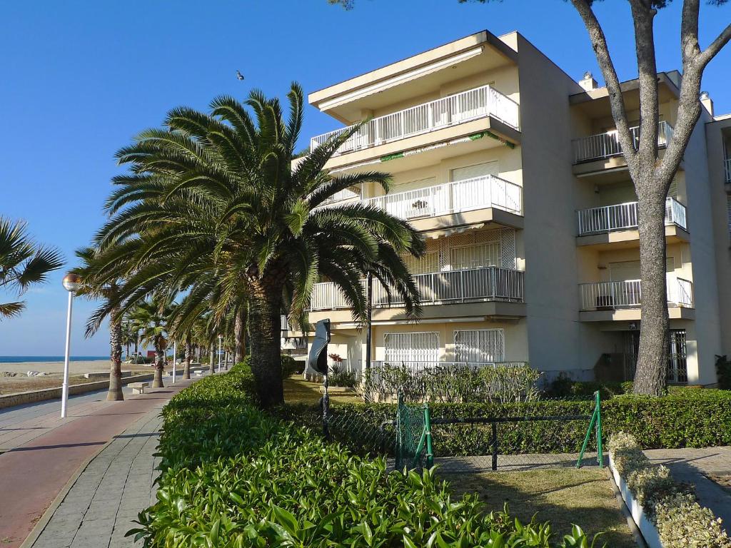 een gebouw op het strand met palmbomen en een stoep bij Apartment DMS V by Interhome in Vilafortuny