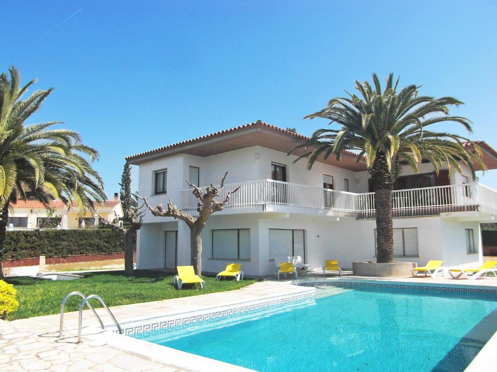 a villa with a swimming pool and palm trees at Holiday Home Eva by Interhome in Sant Antoni de Calonge