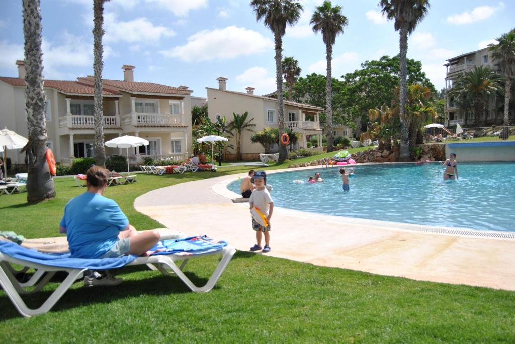 a woman and a child playing in the pool at a resort at HG Jardín de Menorca in Son Bou
