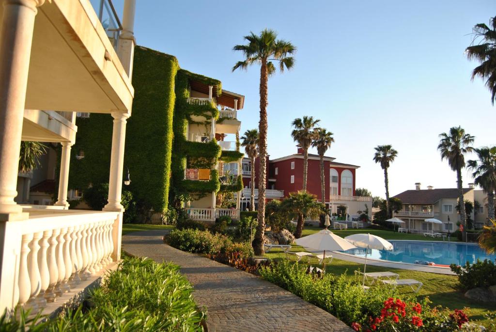 a view of a resort with a swimming pool and palm trees at Aparthotel HG Jardin de Menorca in Son Bou
