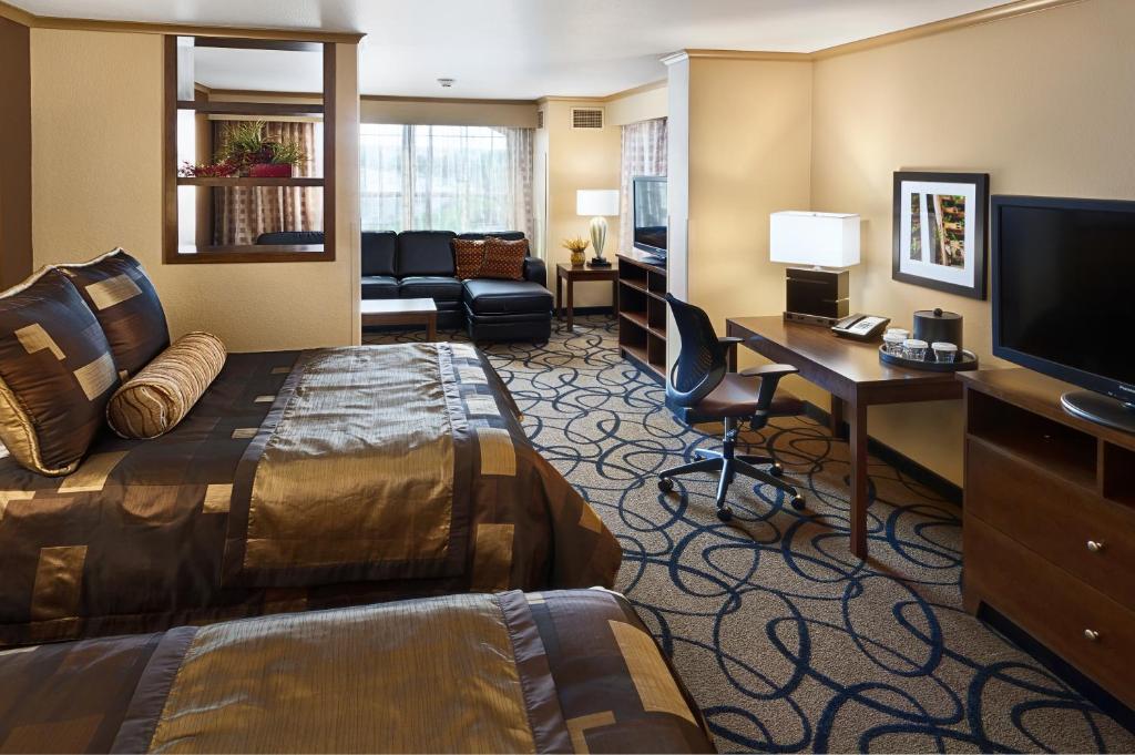 a hotel room with a bed and a desk and a television at ClubHouse Hotel and Suites in Pierre