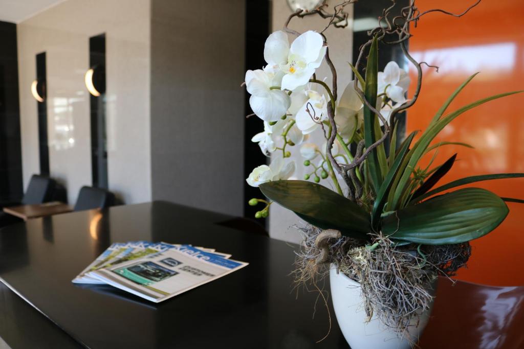 een vaas gevuld met witte bloemen op een tafel bij Hotel DYMINY in Kielce