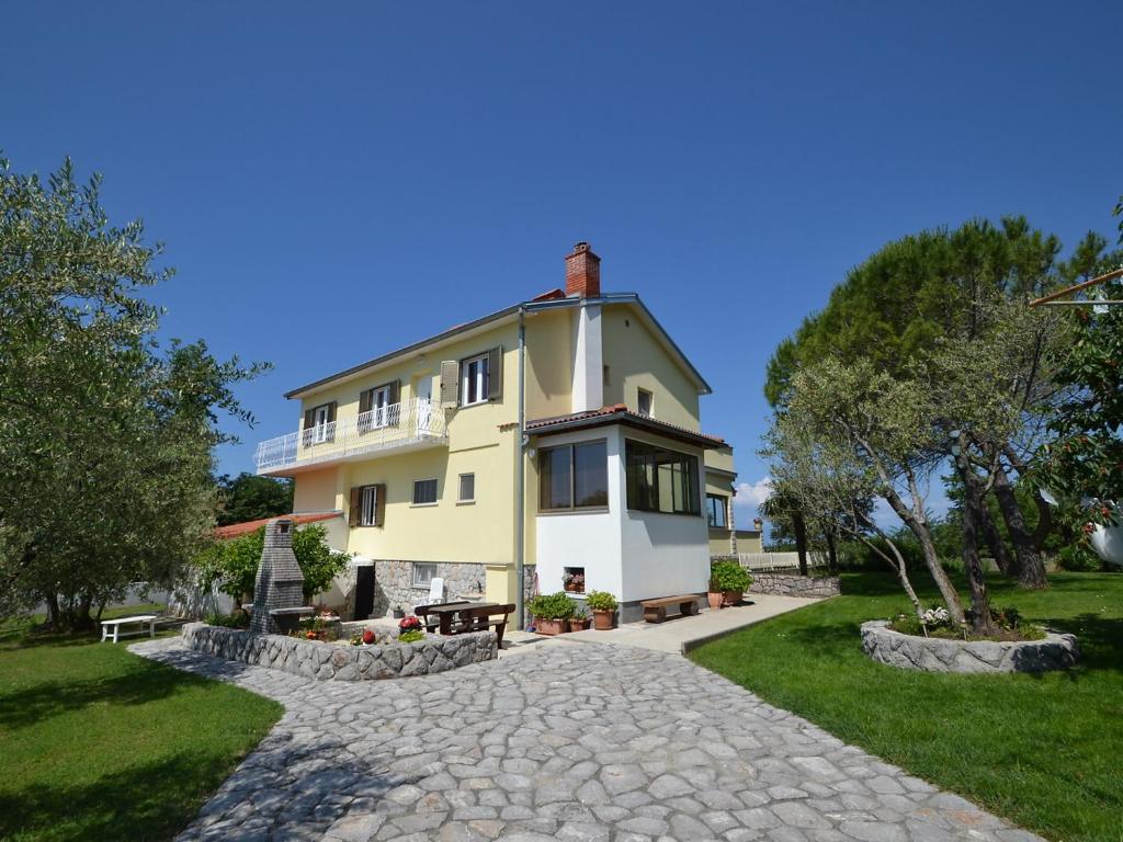 a large yellow house with a stone driveway at Apartment Dada-2 by Interhome in Omišalj