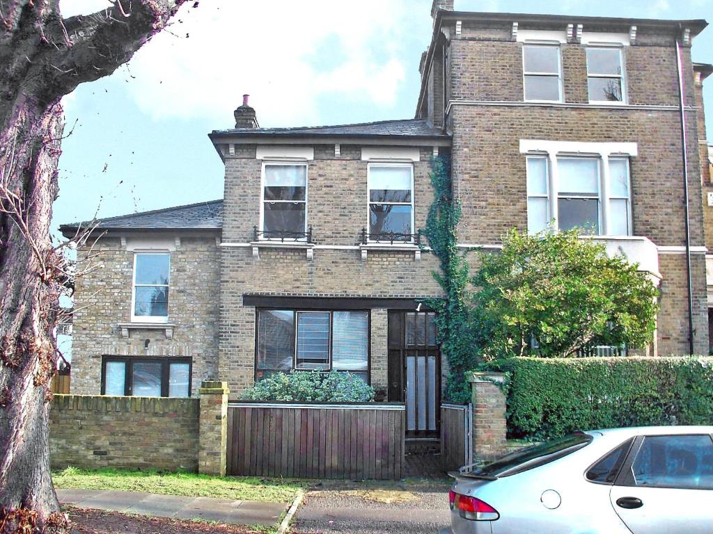 a brick house with a car parked in front of it at Apartment Holly Lodge Coach House by Interhome in London