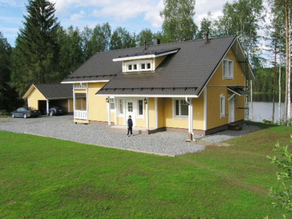a yellow house with a person standing in front of it at Holiday Home Mielikki by Interhome in Kurkimaki