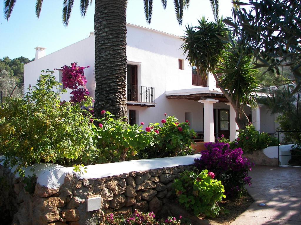 una casa con flores y una pared de piedra en Agroturismo Can Pere Sord, en Sant Joan de Labritja