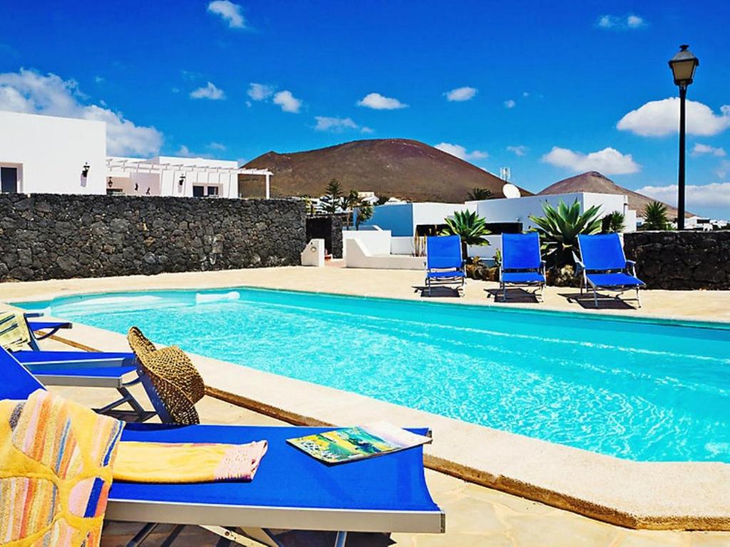 einen Pool mit blauen Stühlen und einem Pool in der Unterkunft Holiday Home Pelzer by Interhome in Conil