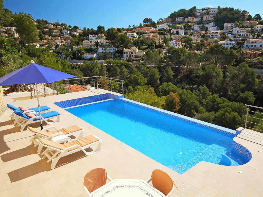 - une piscine avec 2 chaises longues et un parasol dans l'établissement Holiday Home Negrita by Interhome, à Benissa