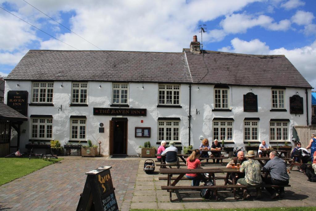 a group of people sitting outside of a white building at The Raven Inn in Ruthin