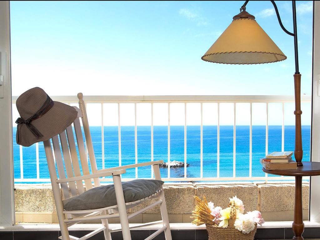 a rocking chair on a balcony with a view of the ocean at Apartment Les Roquetes by Interhome in Calpe