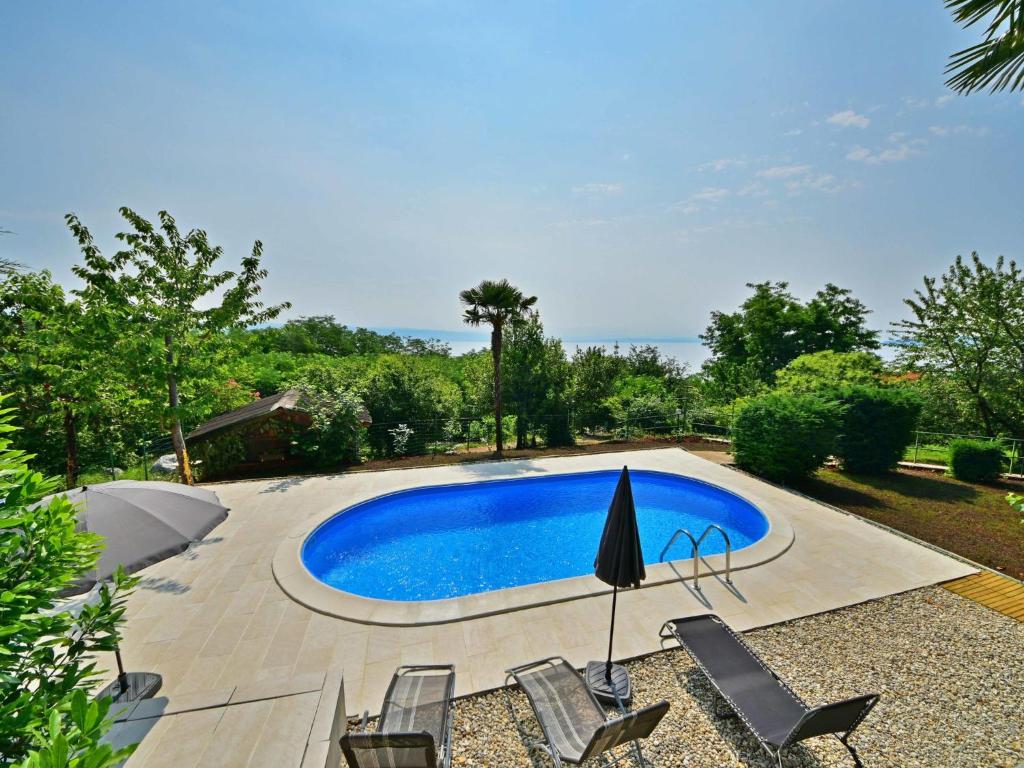 einen Pool in einem Garten mit Stühlen und einem Sonnenschirm in der Unterkunft Apartment Zvonko-1 by Interhome in Lovran