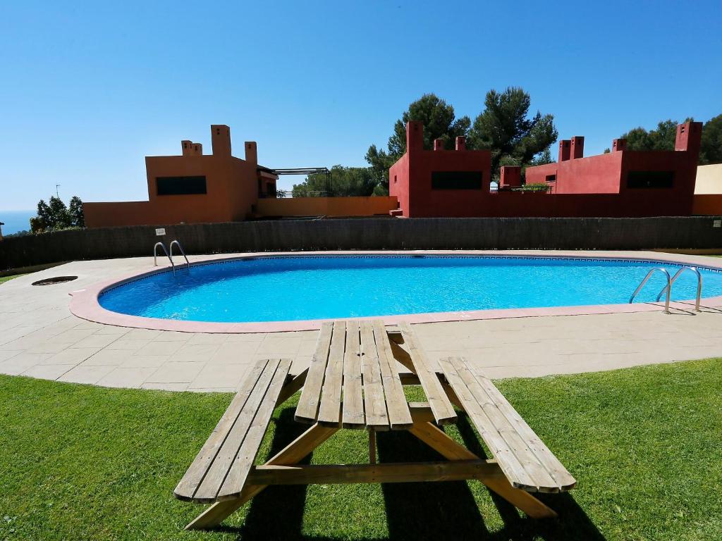 a wooden bench sitting in front of a swimming pool at Holiday Home Vistamar by Interhome in Ferrán