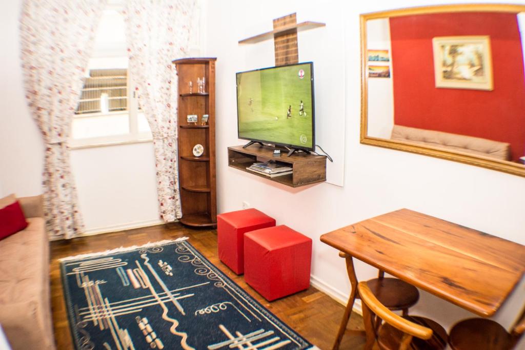 uma sala de estar com uma televisão e uma mesa e uma mesa sidx sidx em Apartamento Djalma Urich no Rio de Janeiro