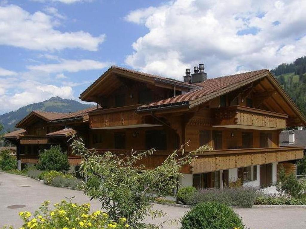 una grande casa in legno con montagne sullo sfondo di Apartment Farfalla by Interhome a Gstaad